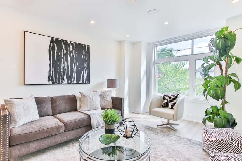 A large black and white canvas hanging above a gray sofa in a bright modern living room